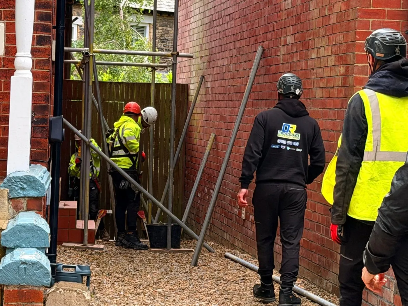 Dunnrite Scaffolding crew erecting a scaffold down the side of a red-brick house in Leeds